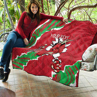 Red quilted Wales blanket held up, featuring Welsh dragon graphic and custom text