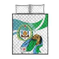 White quilt and two pillow covers with green, blue, and gold patriotic emblem design