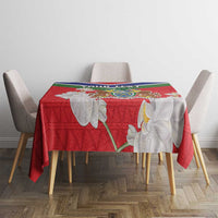 Red Gambia coat of arms tablecloth with white orchid-style flowers on dining table