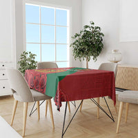 Red tablecloth with green diagonal band and coat-of-arms design on dining table.