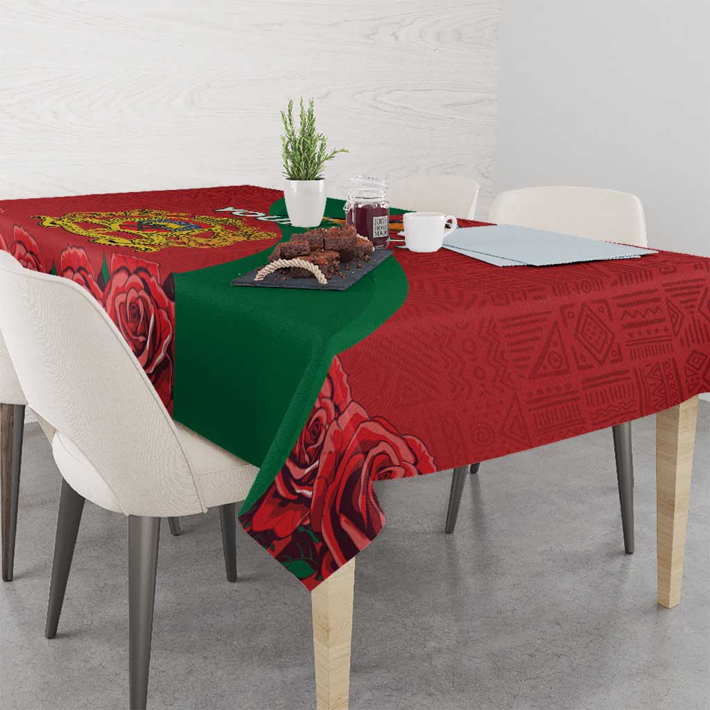 Red tablecloth with green drape and rose print, hanging over dining table edge.