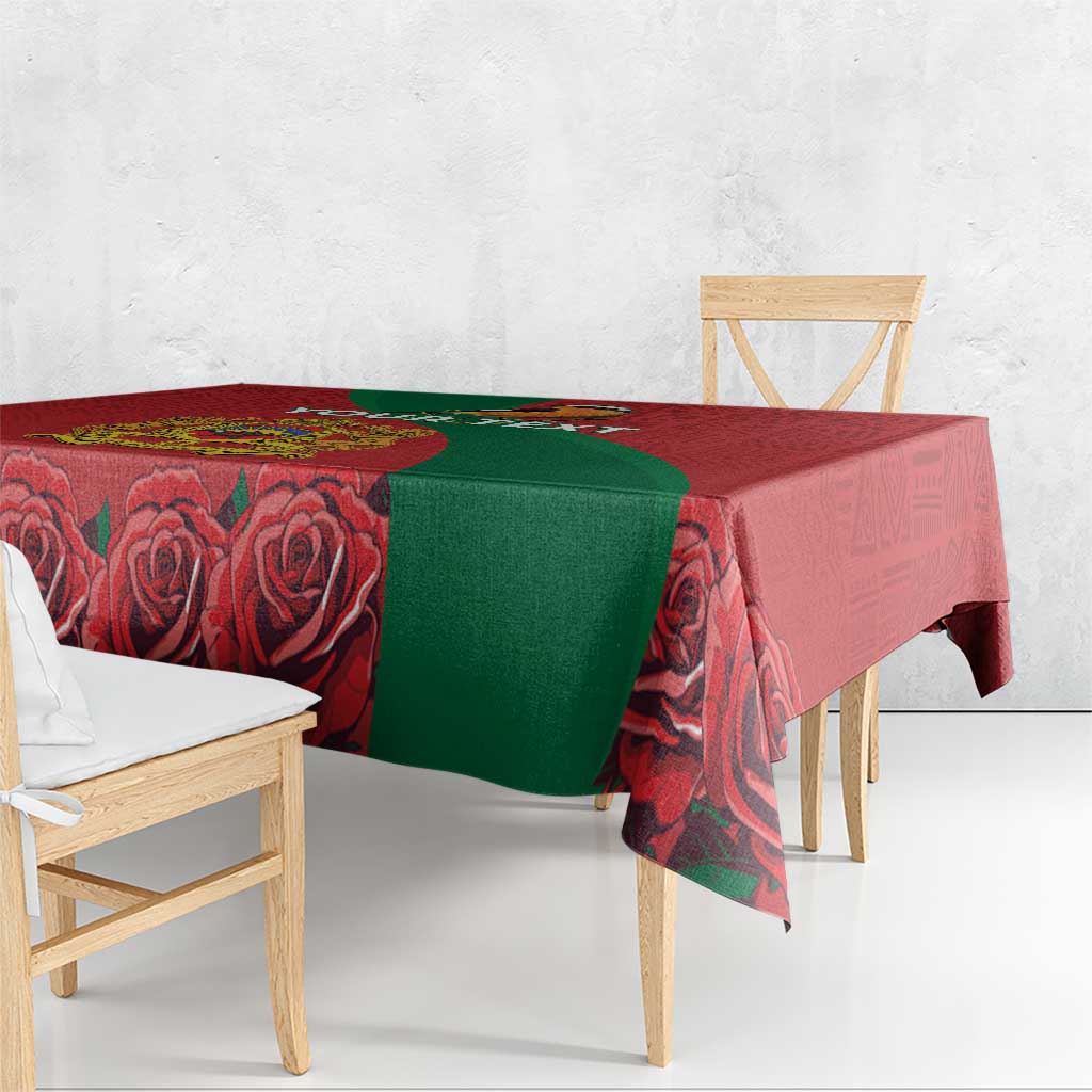 Red tablecloth with green panel and rose motifs on wooden dining table.