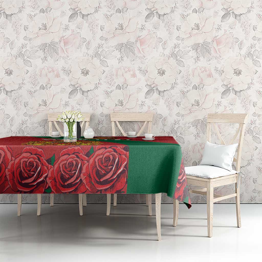 Red and green tablecloth with rose pattern and coat of arms on dining table.