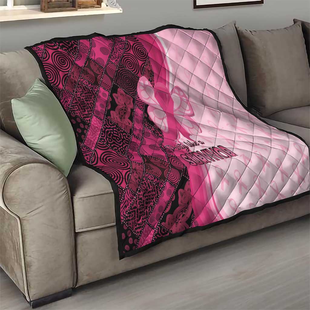 Pink and maroon quilt blanket on a sofa with quilt stitching, ribbon-butterfly emblem, “Survivor”