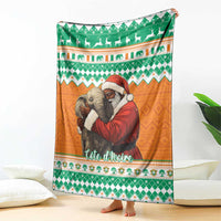 Christmas blanket with green and orange patterned elephants and Santa, draped over bed