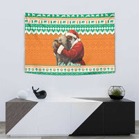 Christmas wall tapestry showing Santa hugging elephants, green geometric border on orange background.