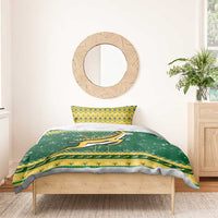 Green duvet and pillow shams with Springbok logo and yellow patterned border on bed