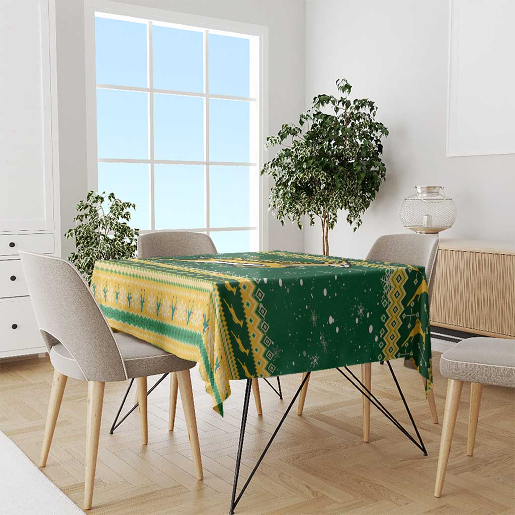 Green and yellow patterned Christmas tablecloth with fringe on dining table