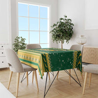 Green and yellow patterned Christmas tablecloth with fringe on dining table