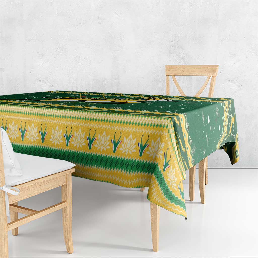 Green and yellow patterned Christmas tablecloth draped over table