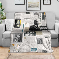 White newspaper-style blanket with Black History collage covering a couch