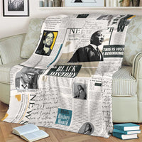 White newspaper-style blanket with Black History collage draped across couch cushions