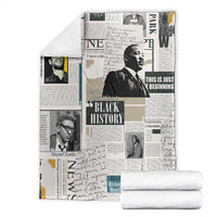 White newspaper-style blanket with Black History collage, folded beside stacked towels