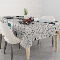 Newspaper print tablecloth with script text and photo figures, draped over tabletop