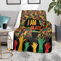 Black History Month blanket on chair, “I AM BLACK” text with multicolor hands and map