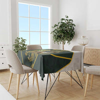 Green patterned tablecloth with yellow-trim edge draped over dining table