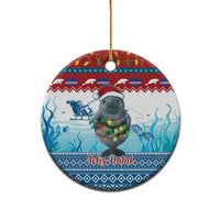 Blue ceramic round ornament with manatee holding glowing lights, “Feliz Natal” text