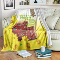 Yellow and white Ethiopian blanket with floral drum design, draped over couch