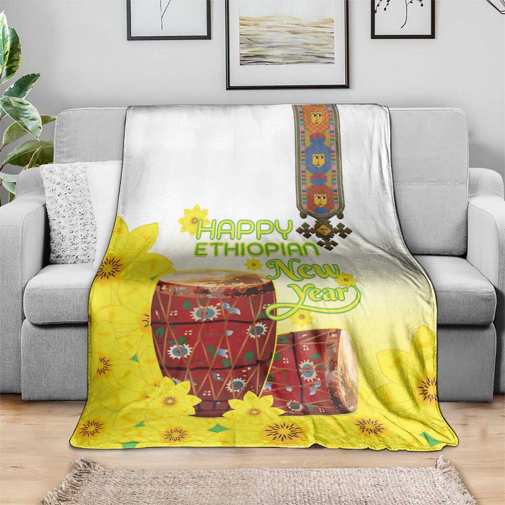 Yellow and white Ethiopian blanket with floral drum artwork, laid over gray sofa
