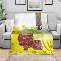 Yellow and white Ethiopian blanket with floral drum artwork, laid over gray sofa