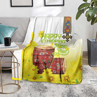 Yellow and white Ethiopian blanket with drum and flower graphics, draped over sofa