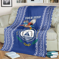 Personalized blue kingfisher blanket with crest emblem and diamond border, draped on sofa