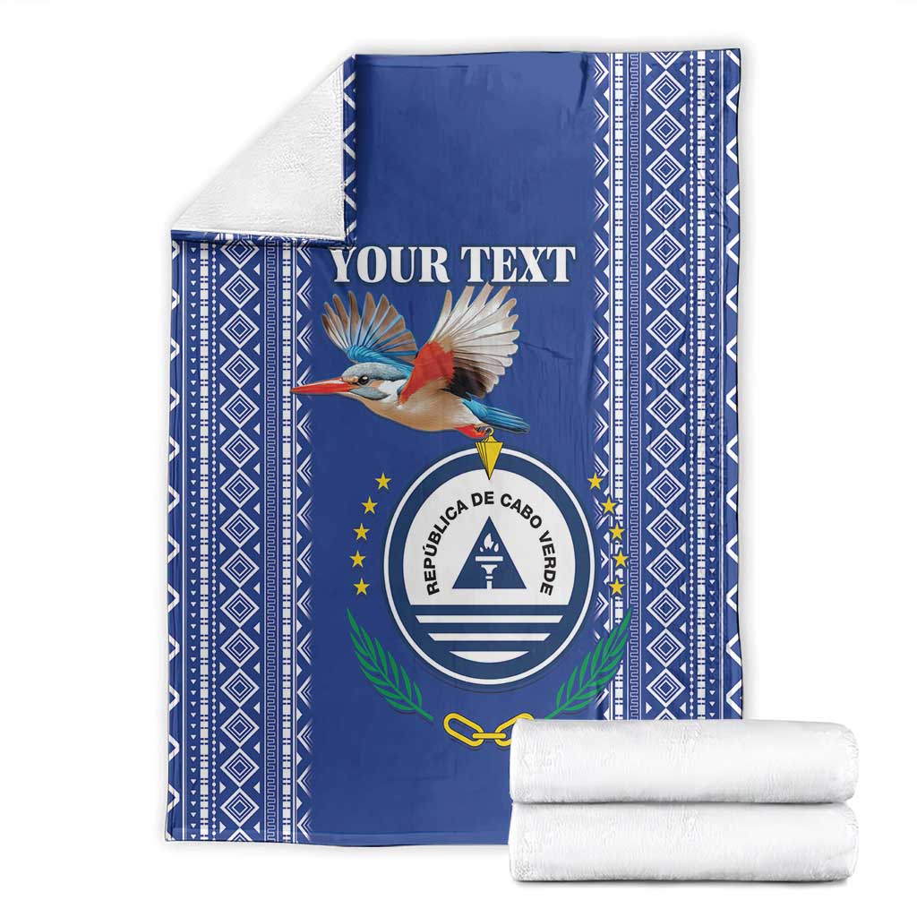 Personalized blue blanket with crest and bird print, shown folded with white stacked towels