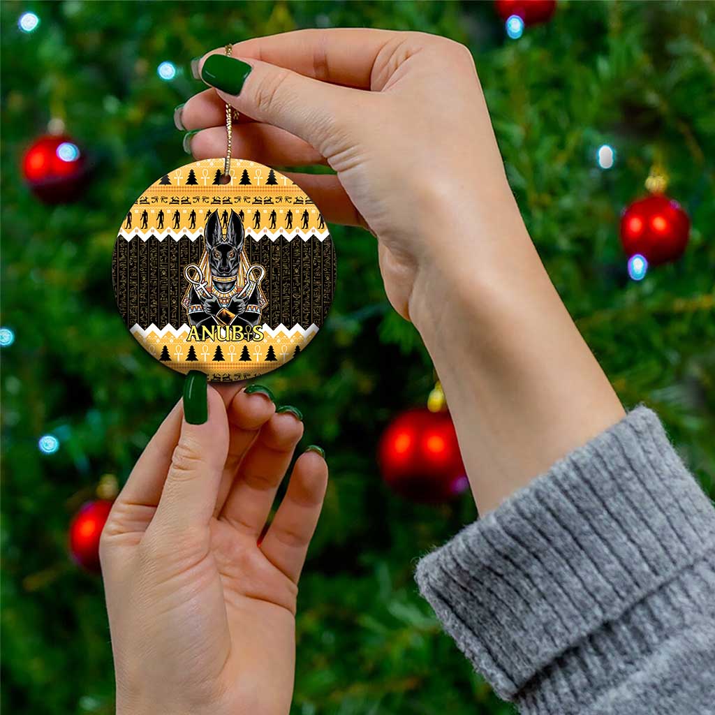 Orange round ceramic Anubis ornament held in hand, with black hieroglyph design and gold loop
