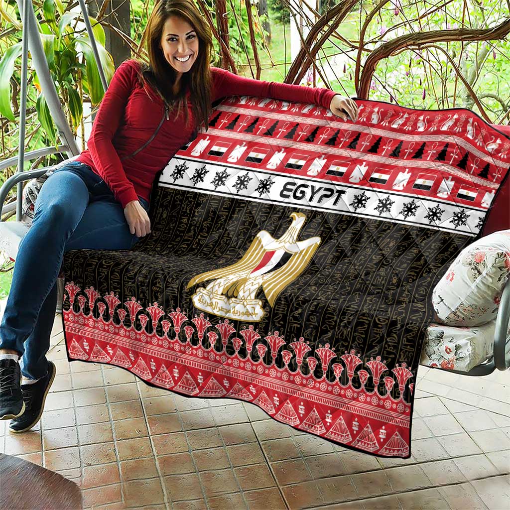 Egypt-themed quilt blanket spread out with red trim, black pattern, and gold coat-of-arms emblem