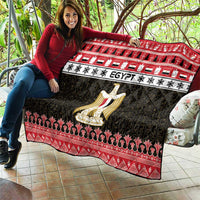Egypt-themed quilt blanket spread out with red trim, black pattern, and gold coat-of-arms emblem