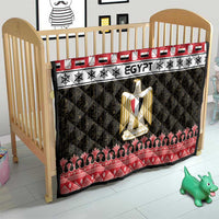 Egypt-themed quilt blanket on baby bed featuring red border, black pattern, and gold coat-of-arms