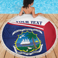 Round Liberia beach blanket with blue graphics, red panel, and white fringe border.