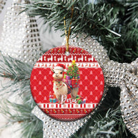 Red round ceramic Christmas ornament with alpaca, Christmas tree, and gold trim on string.