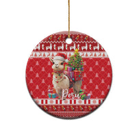 Red round ceramic Christmas ornament with alpaca holding gifts and the text "Peru".