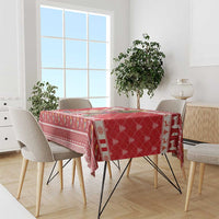 Red Christmas tablecloth with llama and tree border pattern, draped over dining table.