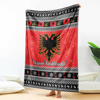Red and black Christmas blanket draped on floor, featuring Albanian eagle and Gezuar Krishtlindja