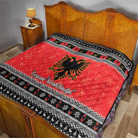 Red quilt blanket with Albanian eagle emblem and black-and-white patterned edge