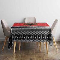 Red Christmas tablecloth on dining table with black geometric trim and hanging sides.