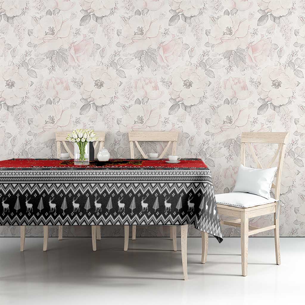 Red and black Christmas tablecloth on rectangular table with patterned center and trim.