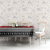 Red and black Christmas tablecloth on rectangular table with patterned center and trim.