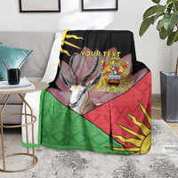 Personalized black blanket on floor with Malawi crest, antelope graphic, red/green geometric pattern