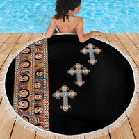 Round black beach blanket with white fringe and four embroidered cross motifs
