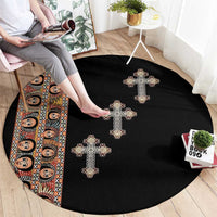 Black round carpet with gold-beige cross motifs, partial tribal border panel on left