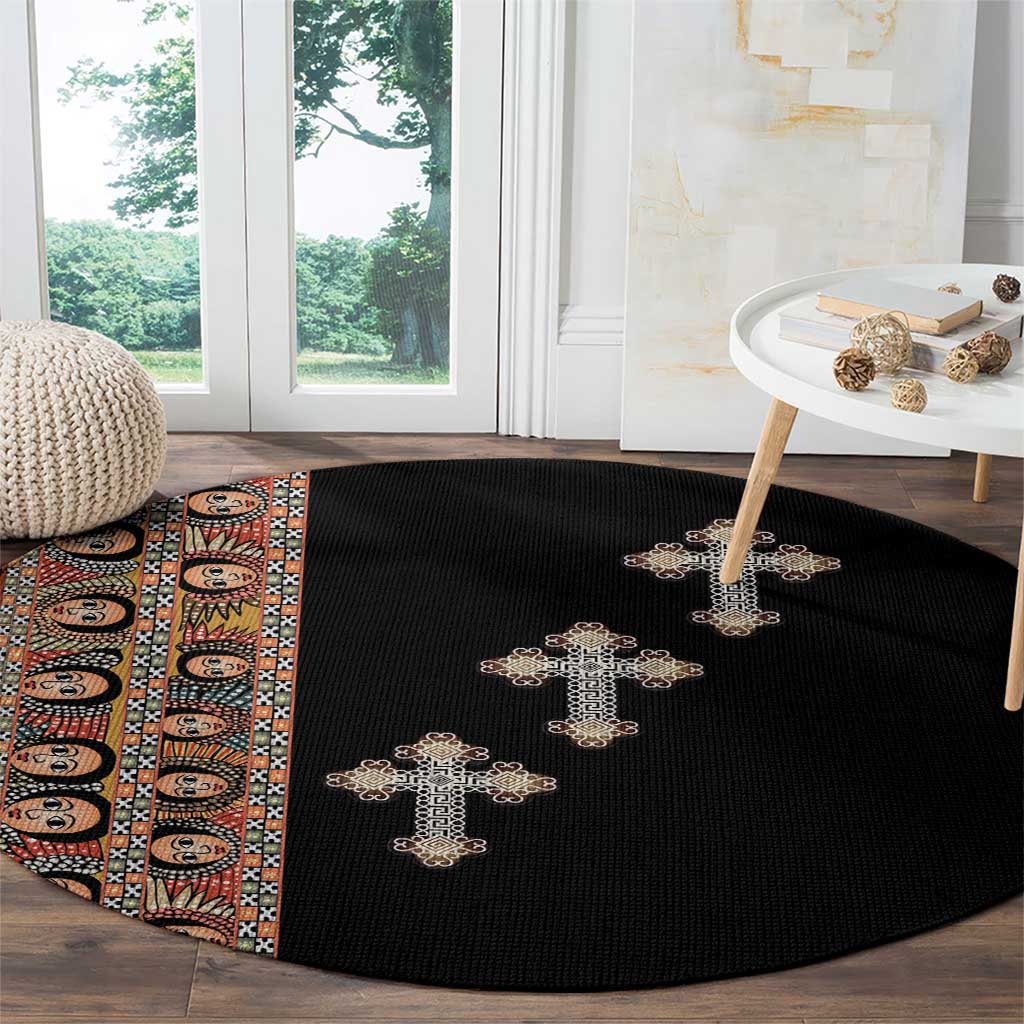 Black round carpet with beige cross embroidery, partial tribal stripe at left