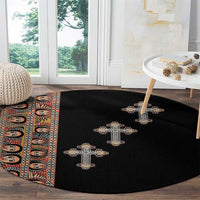 Black round carpet with beige cross embroidery, partial tribal stripe at left