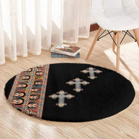 Black round carpet with three beige crosses and tribal stripe border on left edge