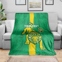 Green football blanket with yellow lion graphic and shield emblem, spread on couch