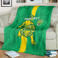 Green football blanket with yellow lion graphic and shield emblem, folded over sofa arm