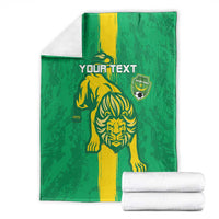 Green football blanket with yellow lion graphic and shield emblem, stacked with white towels