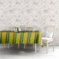 Green and yellow striped cricket tablecloth on a dining table with flowers and plates